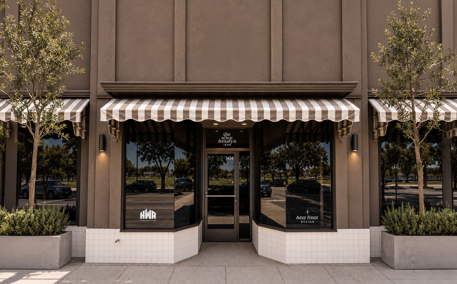 The storefront of The A&M House, striped awnings above black-framed windows, flanked by olive trees, with the a&m house signage on the facade.