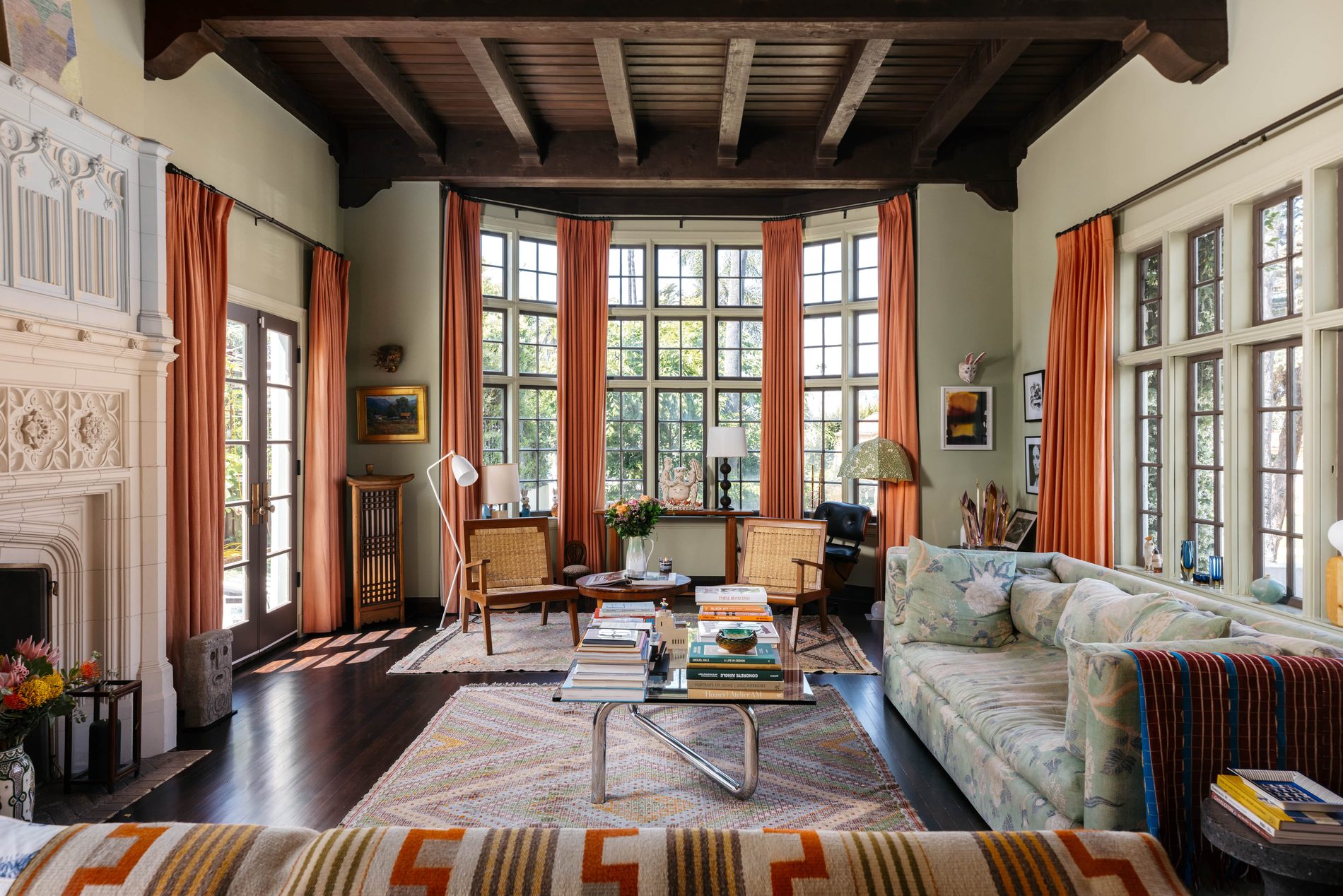 A grand living room with beamed ceiling and tall windows.